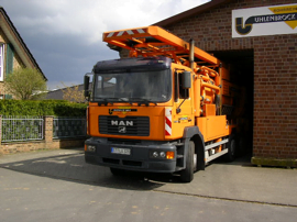 Orangener Spülwagen von Uhlenbrock Rohrreinigung fährt aus einer Halle heraus.